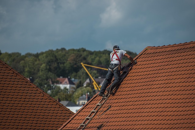 A man works on the roof while wearing safety gear.